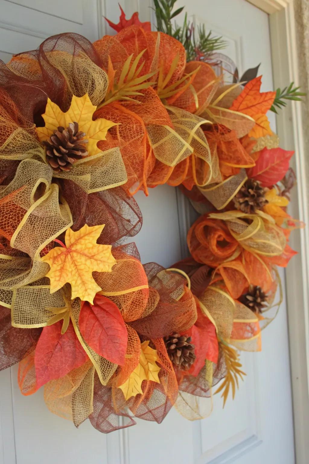 A wreath in classic autumnal colors, featuring deco mesh and fall foliage.