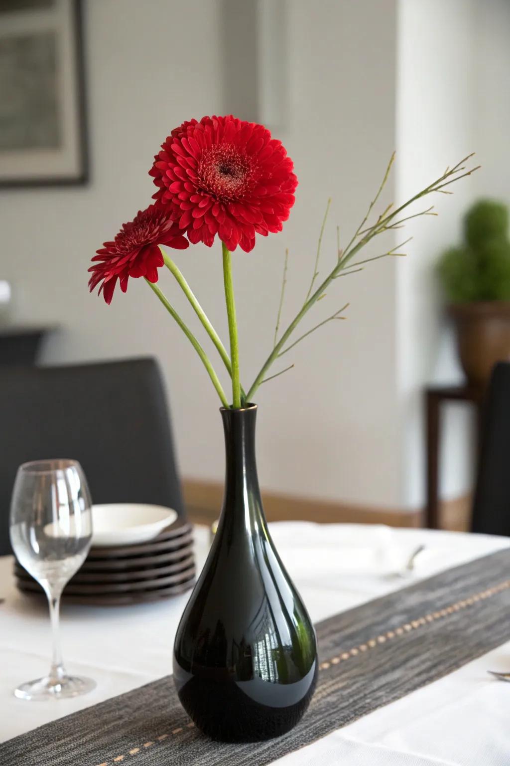 A singular scarlet bloom displayed inside a dark receptacle for a minimalist and outstanding centerpiece.
