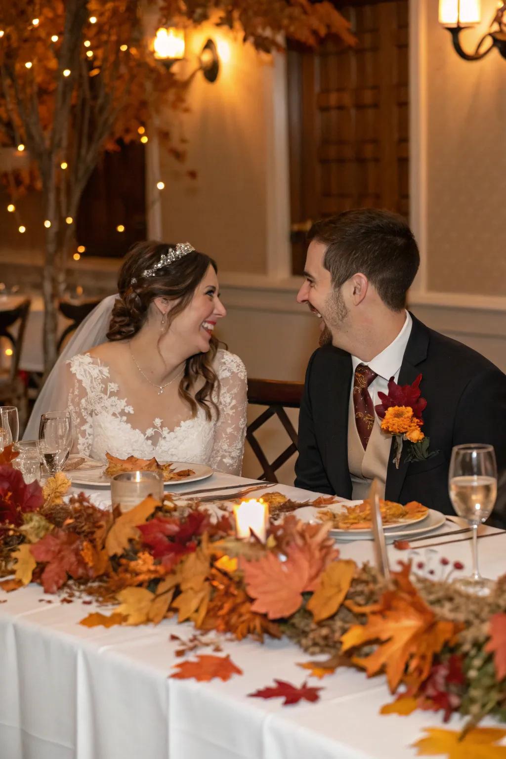 A bride and groom table adorned with seasonal décor such as autumn foliage.