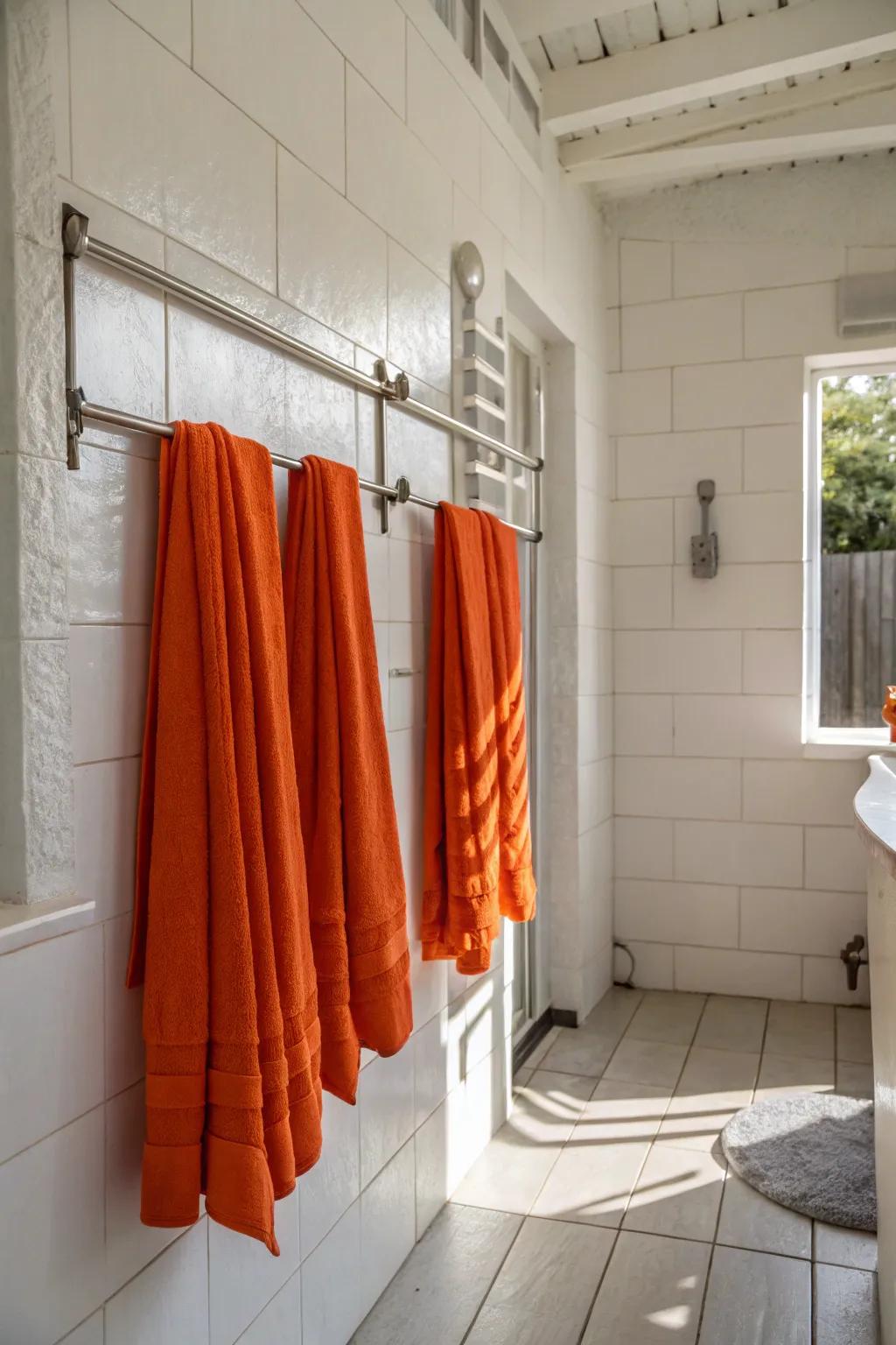 A pristine white bathroom is livened up with bright orange towels, adding a splash of color.