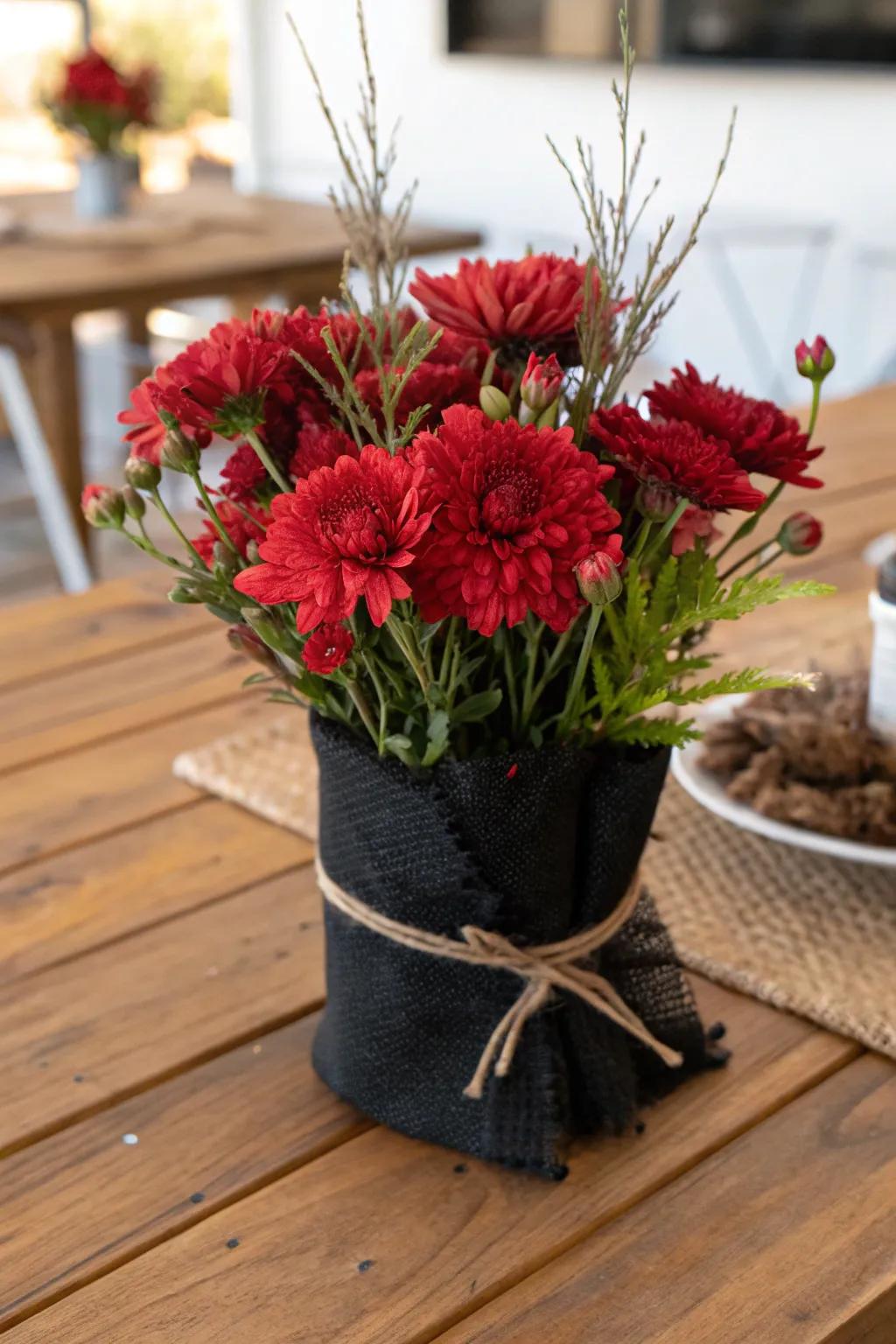 A countryside centerpiece featuring scarlet flowers swathed within dark sackcloth.