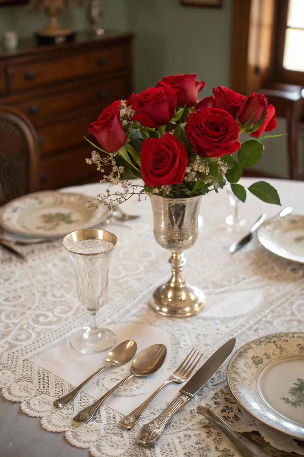 A vintage centerpiece styled with antiquated silverware and scarlet roses to communicate traditional refinement.